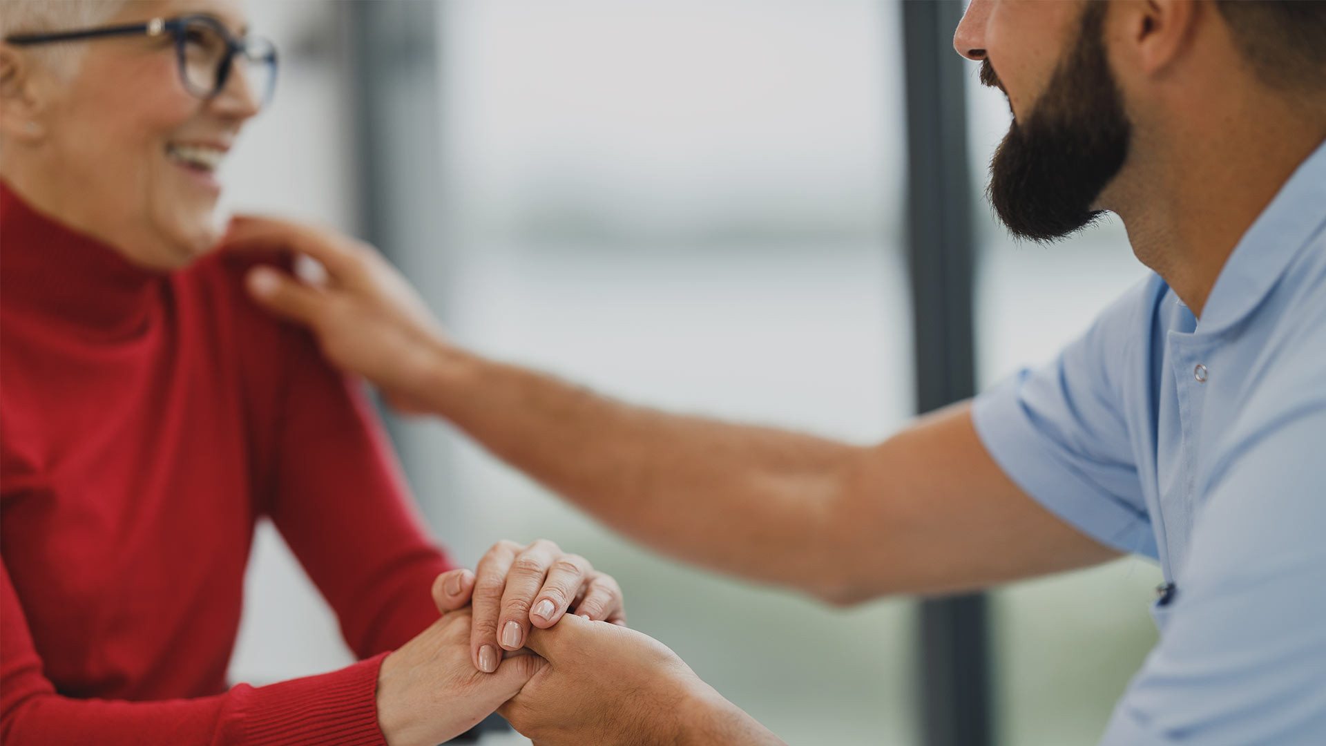 Elderly person holding hands with a carer, representing dementia support in the UK